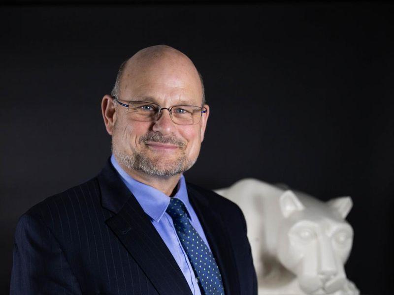 Kevin Snider, chancellor, stands in front of lion shrine statue